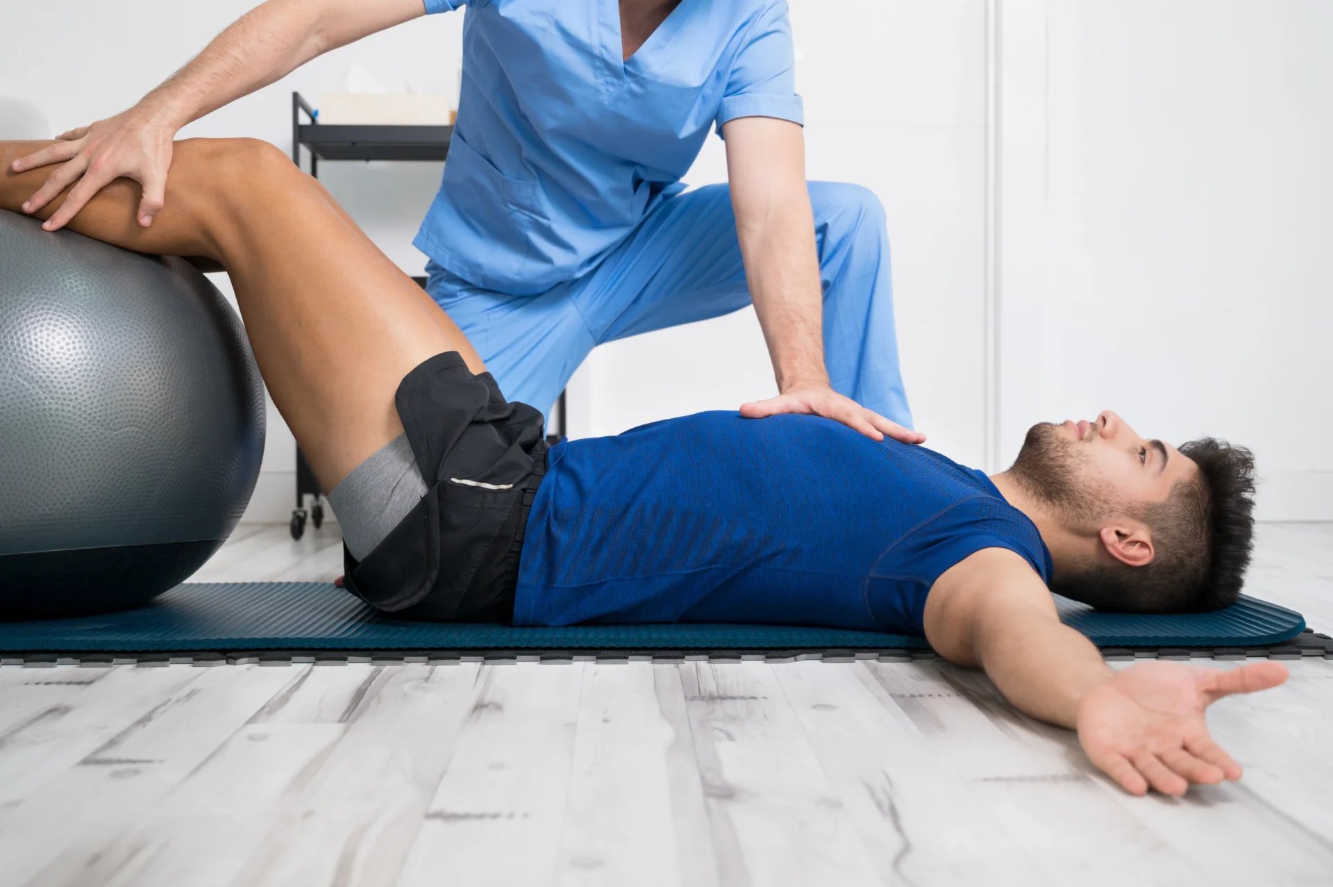 Trainer assisting patient with exercise ball.