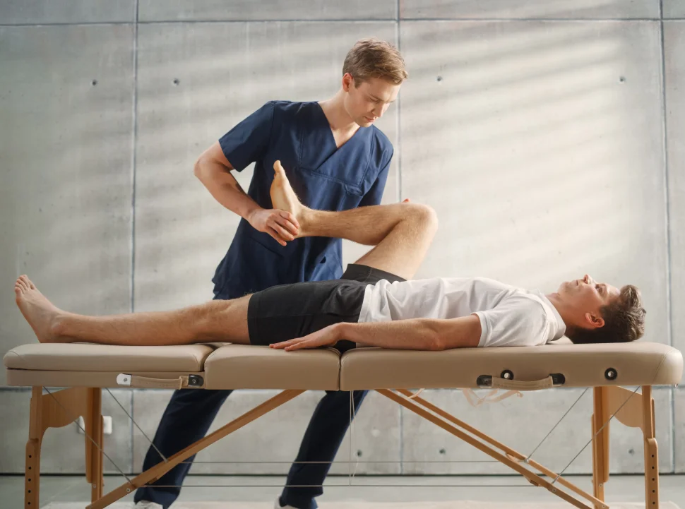 Trainer stretching patient's leg.