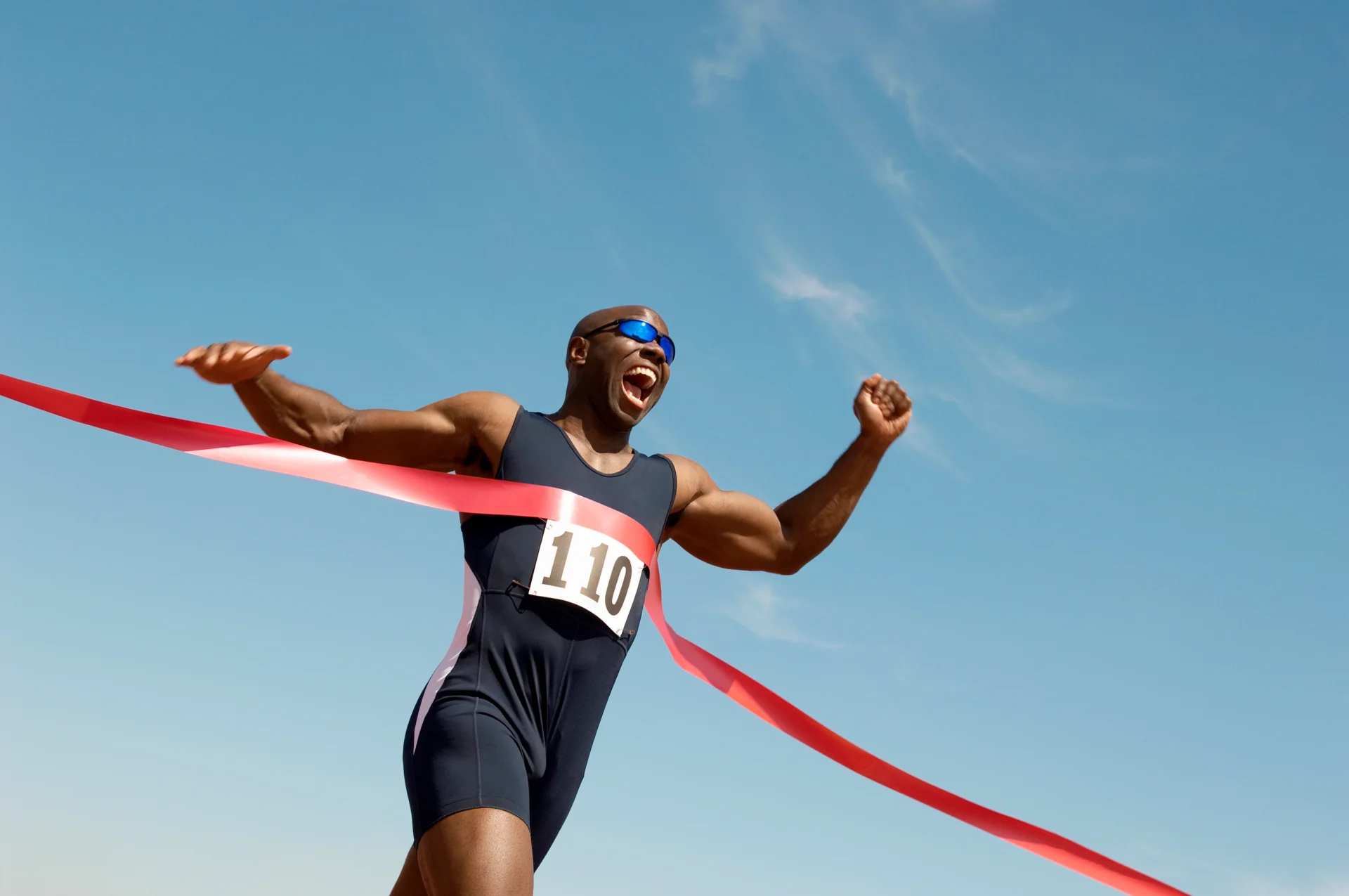 Runner crosses finish line, victorious.